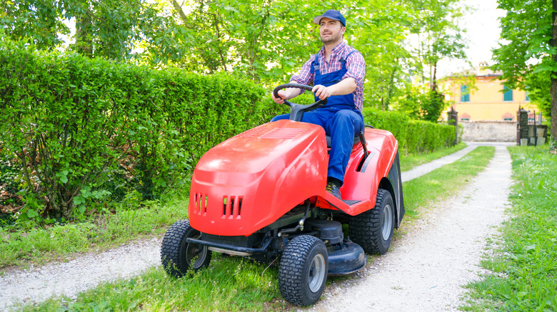 A man cutting the drive on a riding lawn mower