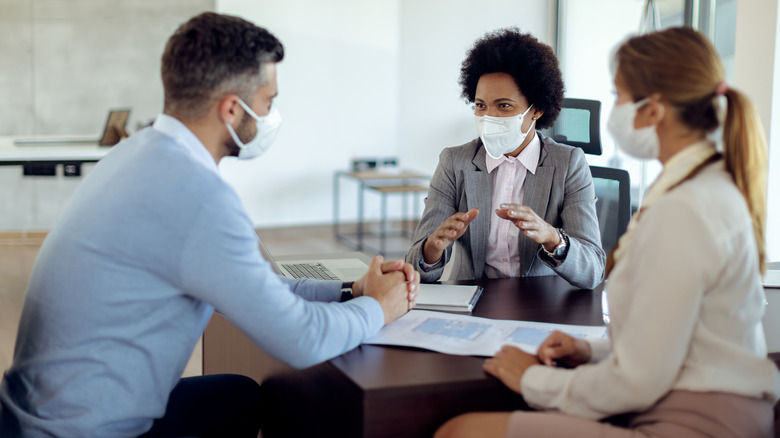 Masked people discussing real estate