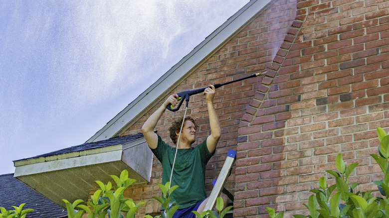 Man power-washing brick exterior