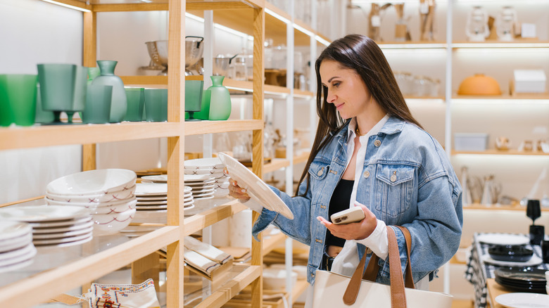 Young woman looking for new plates at store of household good