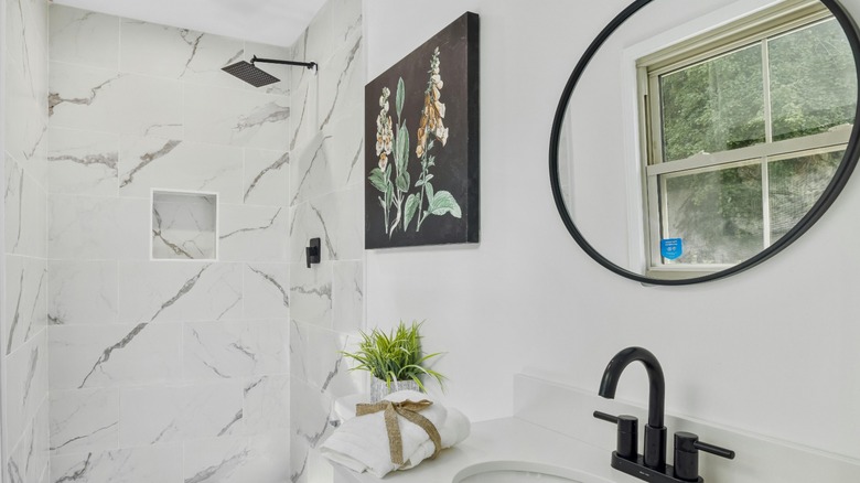 Black floral painting in white bathroom