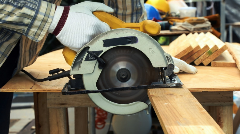 A man using a circular saw to cut through a board