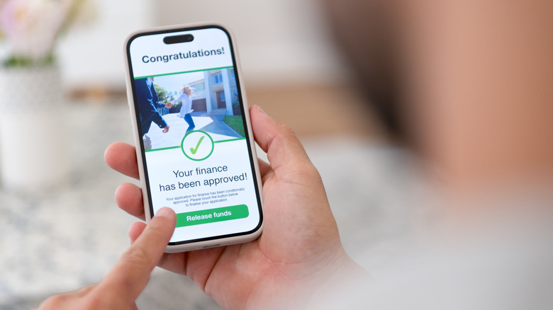 Person holding a smartphone with a loan approval on the screen