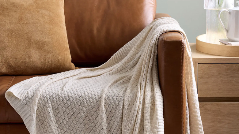 Quince Cotton Cashmere Knit Throw in Ivory draped over leather sofa