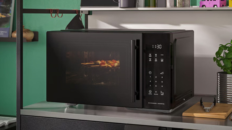 The IKEA GÅTEBO microwave inside of a green kitchen.