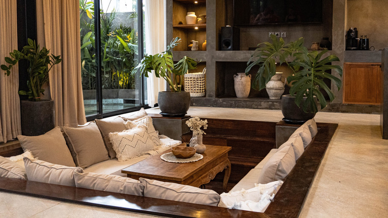 Sunken lounge in a modern living room with comfortable seating, plants, and TV