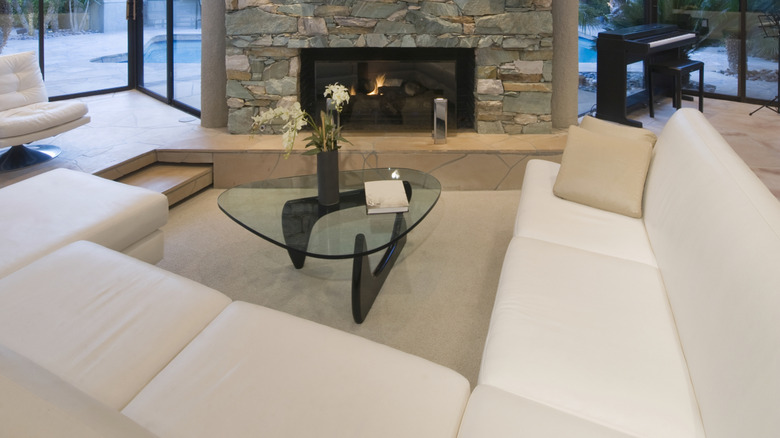 1970s style sunken living room with stairs, minimalist furniture, and fireplace.
