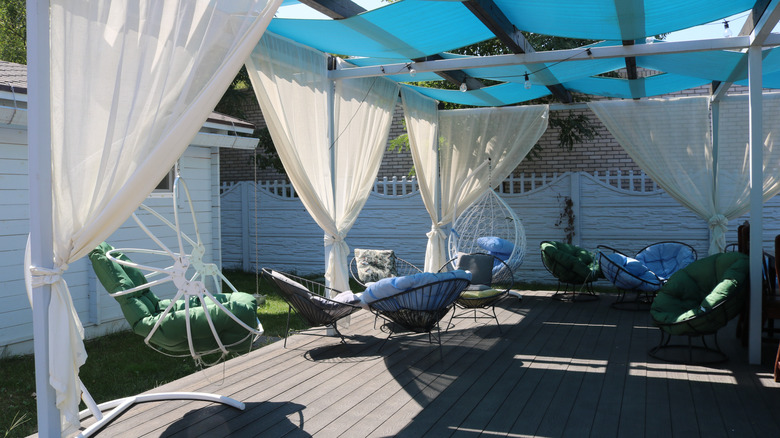 simple covered patio with blue canopy and white curtains with plenty of seating