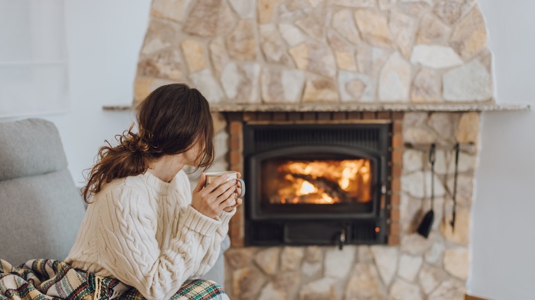 Woman sitting by a brick fireplace