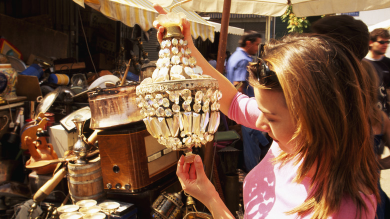 A woman looking at an antique light fixture at a flea market