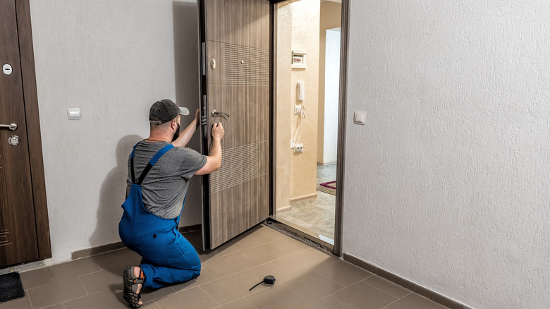A locksmith removing an old knob from a front door.