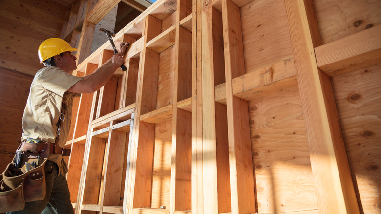 man working on wooden home framing with blocking