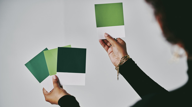 Woman holding and comparing green paint chips