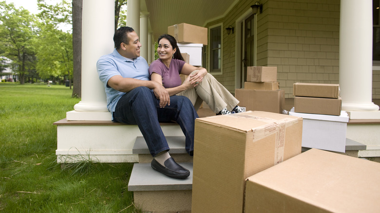 Couple sitting outside home with boxes