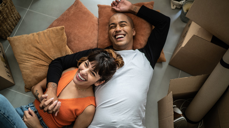 Laughing couple lying on floor of home