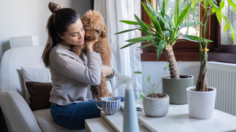 Woman And Her Dog sitting near indoor plants