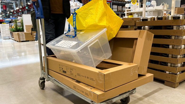 An Ikea shopper loads a cart with goods in boxes.