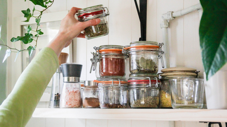 A woman's hand stacks spices on a shelf