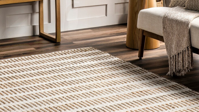 A brown and white patterned entry rug with an upholstered bench