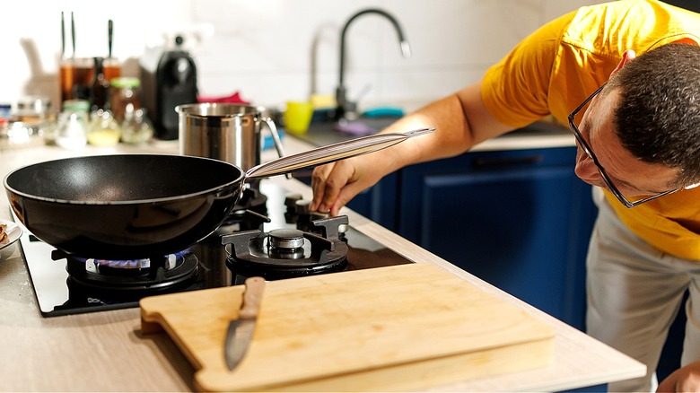 Close-up of person turning on gas stove top and bending to look at the flame