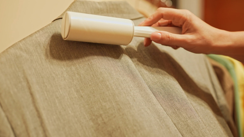 closeup of person using lint roller on blazer
