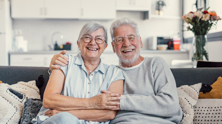 Elderly man and woman sitting on sofa smiling