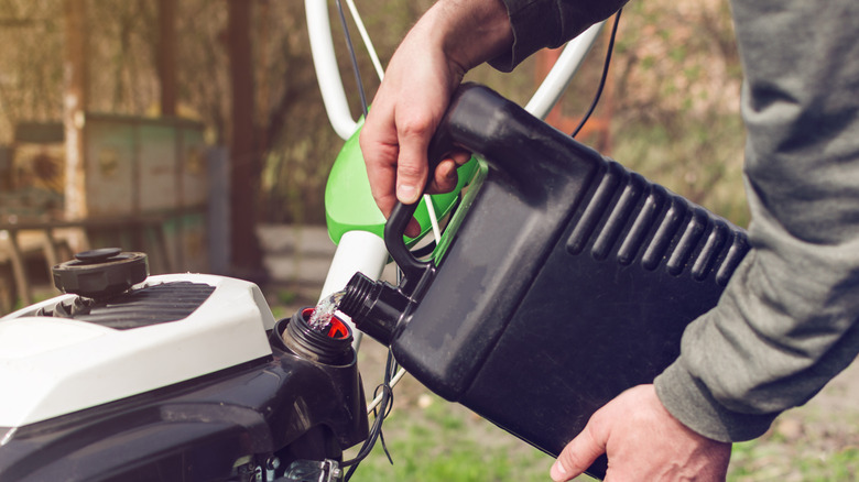 A person putting gasoline into a mower
