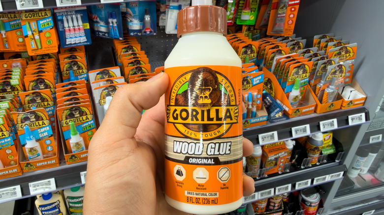A hand holding a bottle of Gorilla wood glue in a store