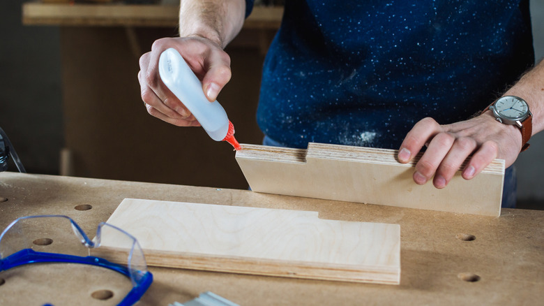 A carpenter using wood glue in their workshop