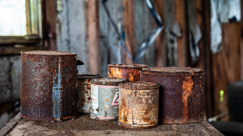 Old, rusted cans of wood stain in a garage