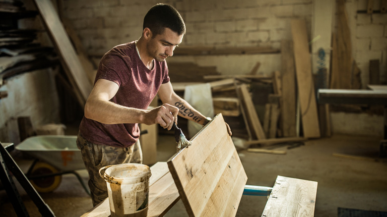 Person applying wood stain to wood in a workshop