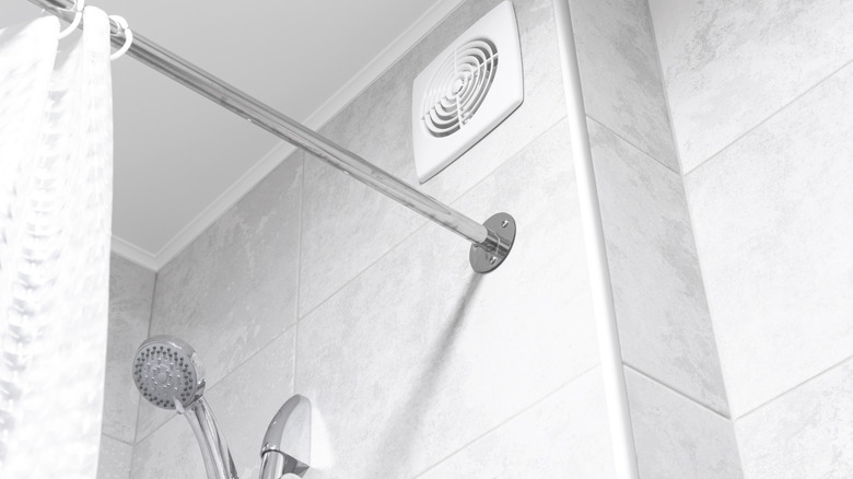 A bathroom fan above a modern white tiled shower