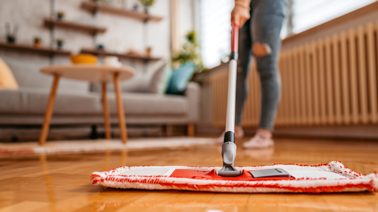 A woman cleans her laminate flooring using a mop system.