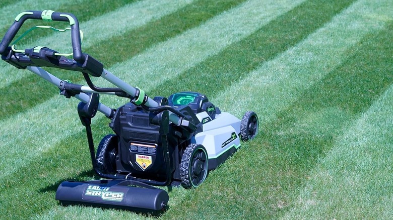 A lawn mower with a striping kit attached to the back of it.