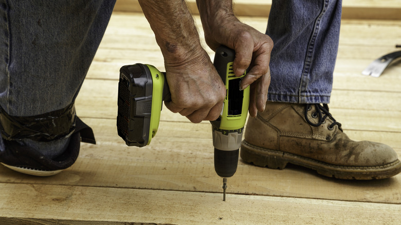 A person using a cordless Ryobi power drill