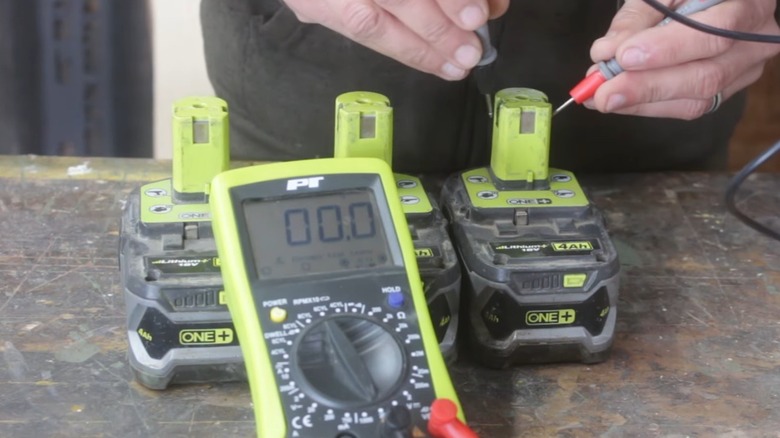 A person testing the charge in a Ryobi battery