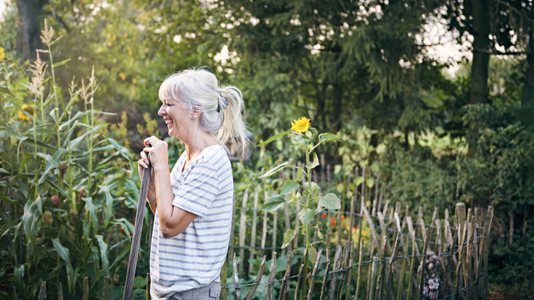 A woman stands in her garden surrounded by sunflowers