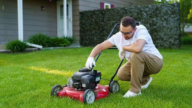 Man checking oil level in lawn mower