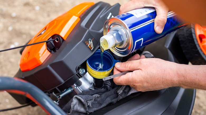 Person dumping fresh oil into lawn mower