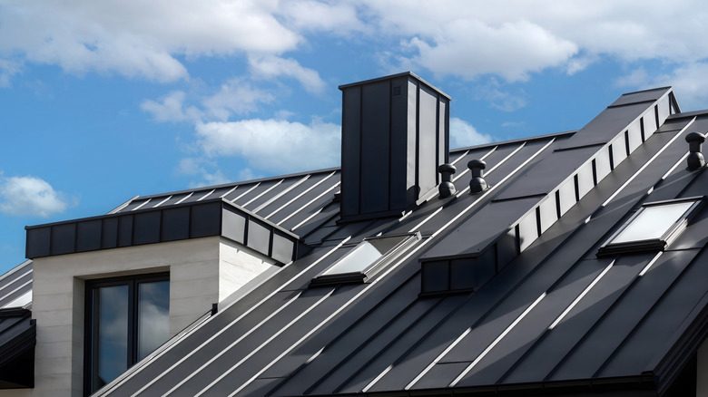 The roof of a modern home with a dark gray metal roof and skylights