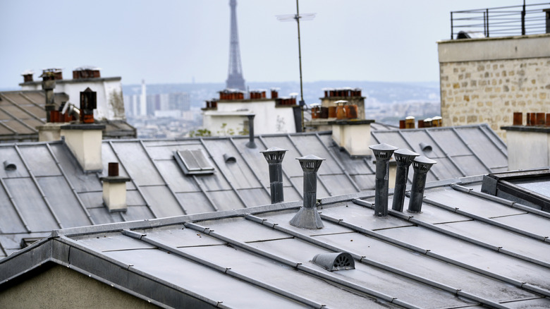 An iconic zinc roof in Paris, France with the Eiffel Towel in the background.