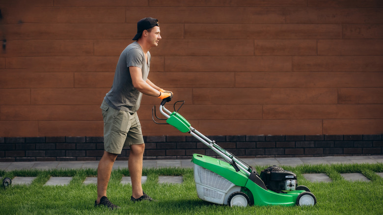 Man mowing with a green cordless electric push mower