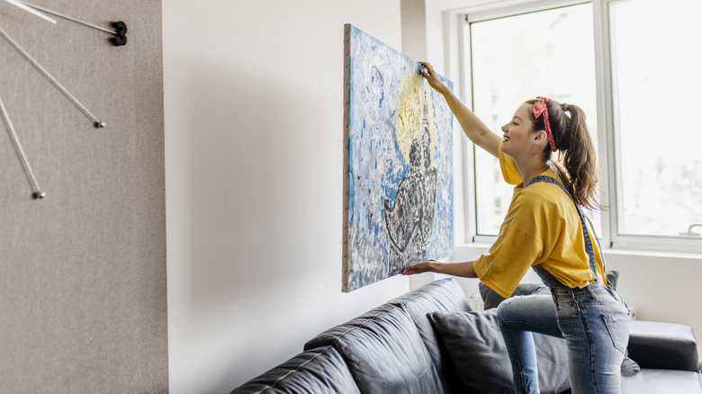 Woman hanging artwork on wall