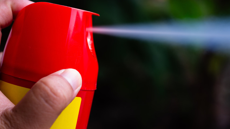 Hand squirting a red can of pesticide
