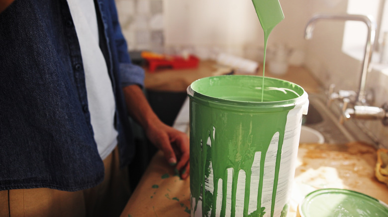 Person inspecting opened can of green paint