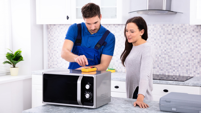 Handyperson repairing countertop microwave