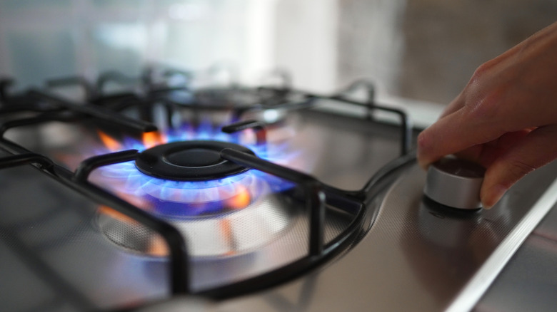 Woman turning on the gas burner on the stove.