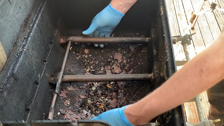 Person replacing burners in a Weber gas grill