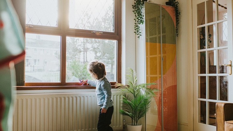 Child playing in front of a window in a home