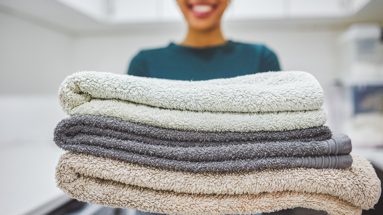 Woman holding freshly cleaned and folded bath towels